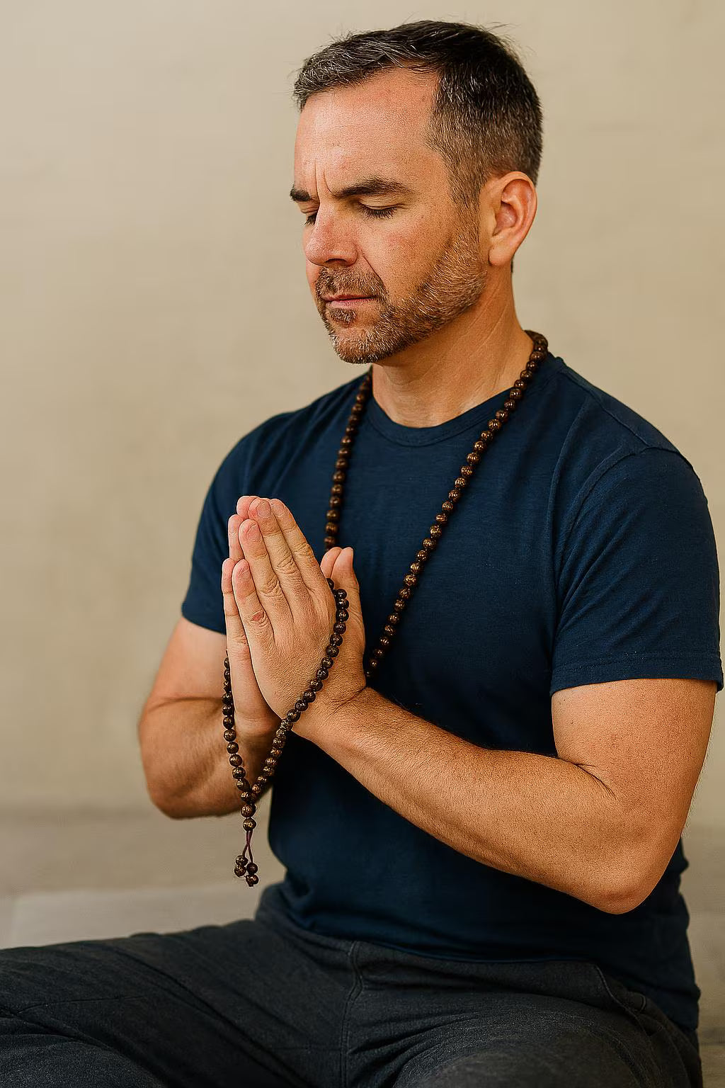 Man meditating with hands clasped and beads in a casual setting