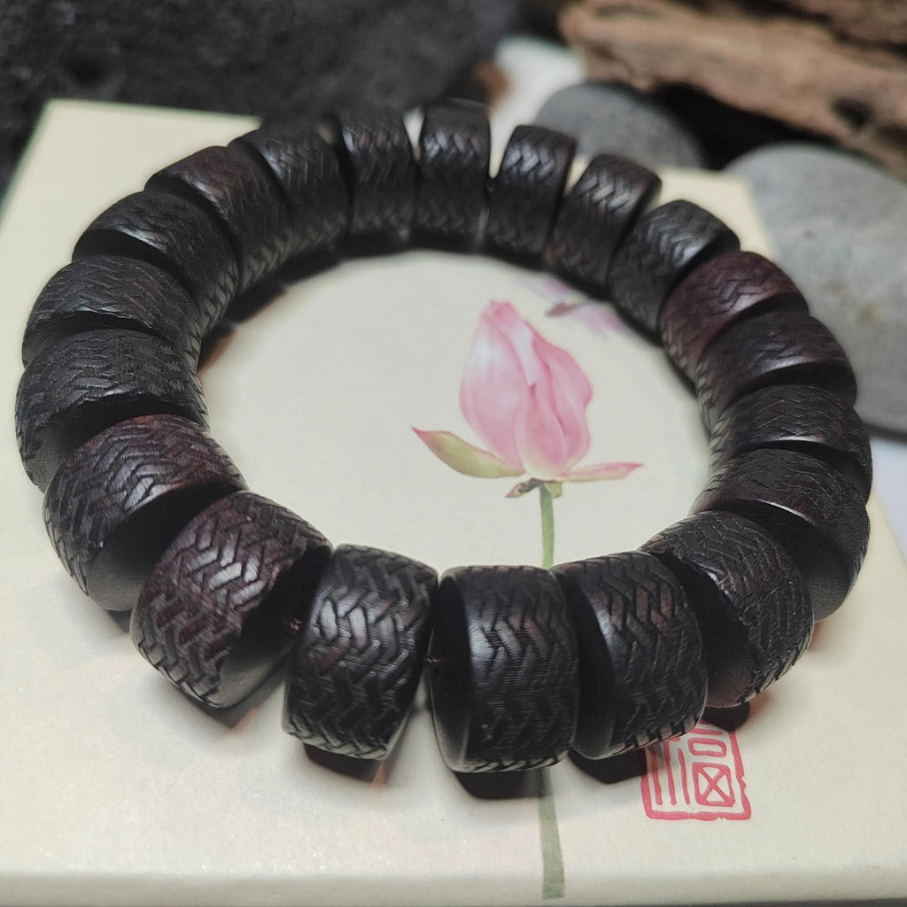 Black beaded bracelet on a white surface with a pink flower illustration