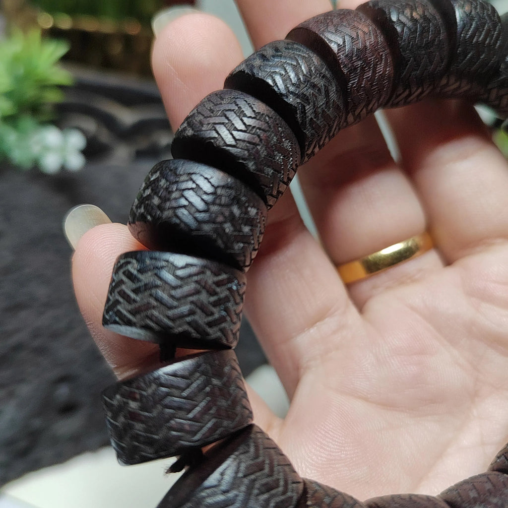 Close-up of a hand holding a textured bracelet with a blurred background