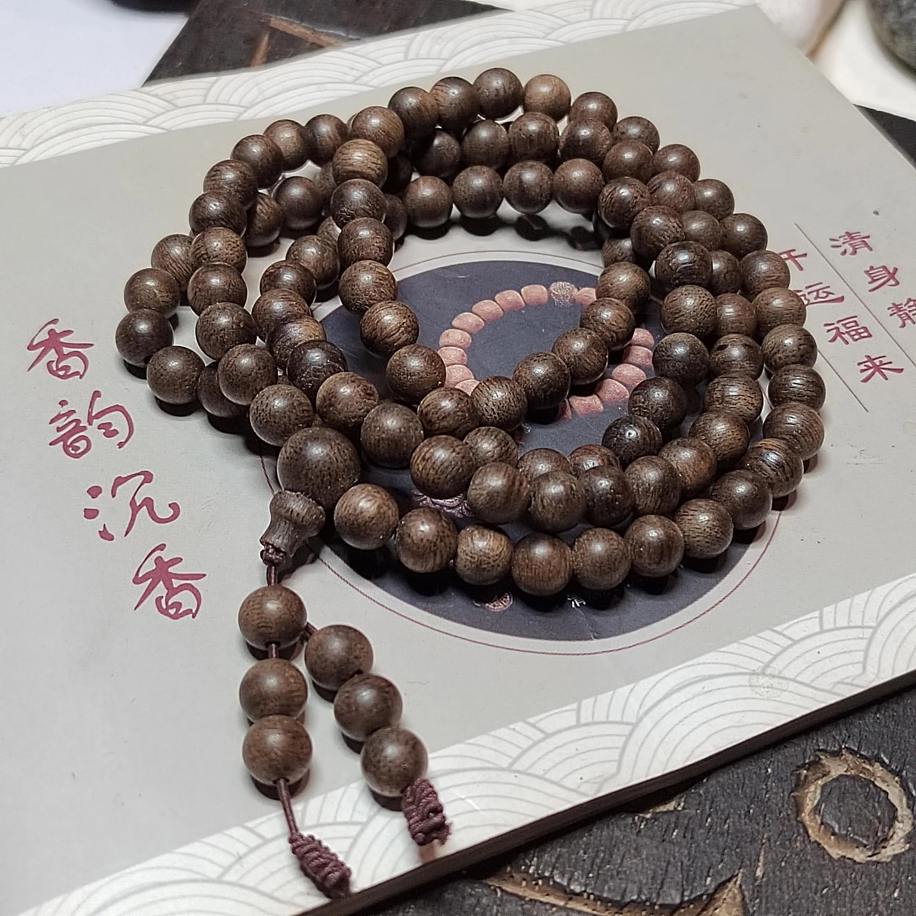 Wooden prayer beads on a textured surface with Chinese characters