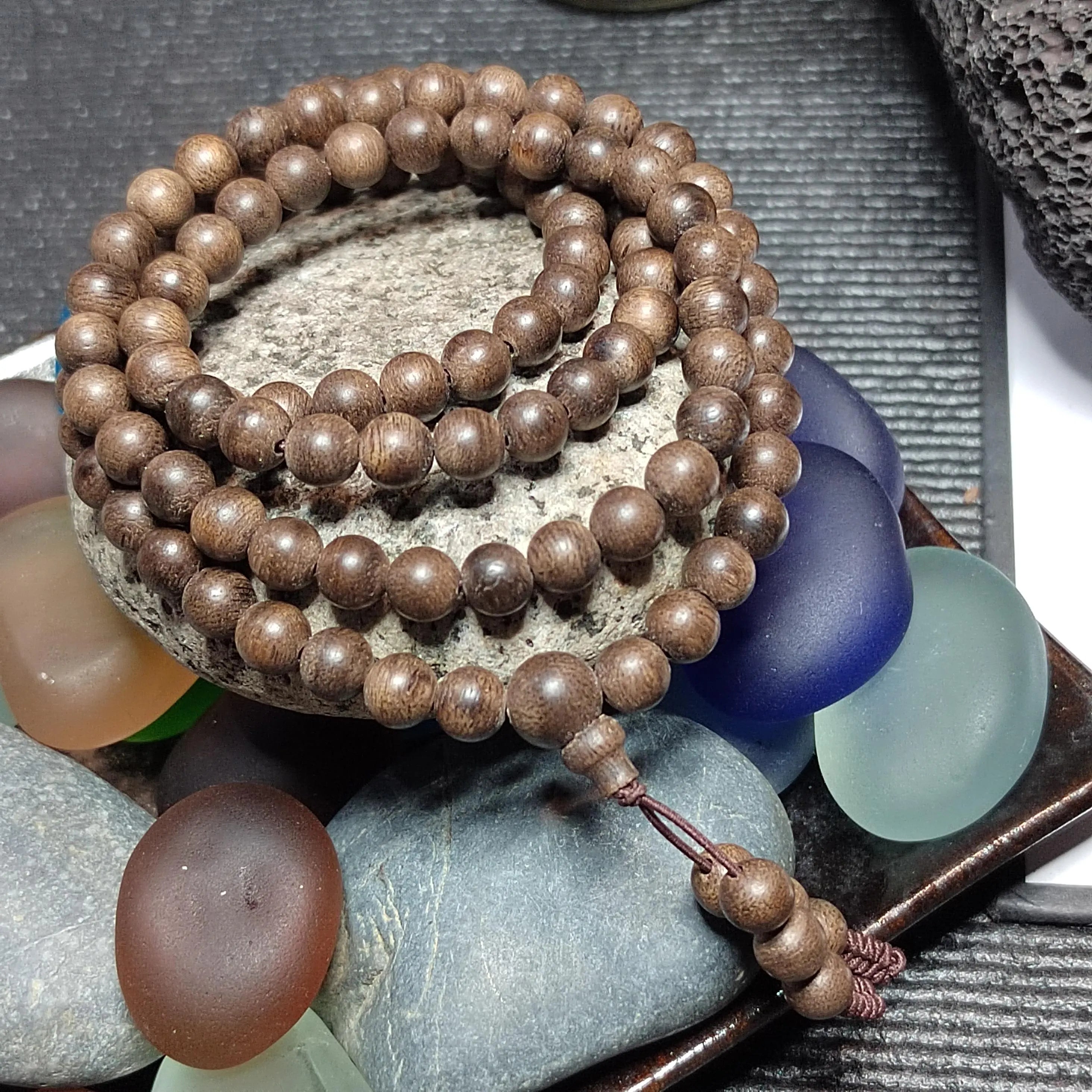 Wooden beaded bracelet on a stone surface with colorful stones