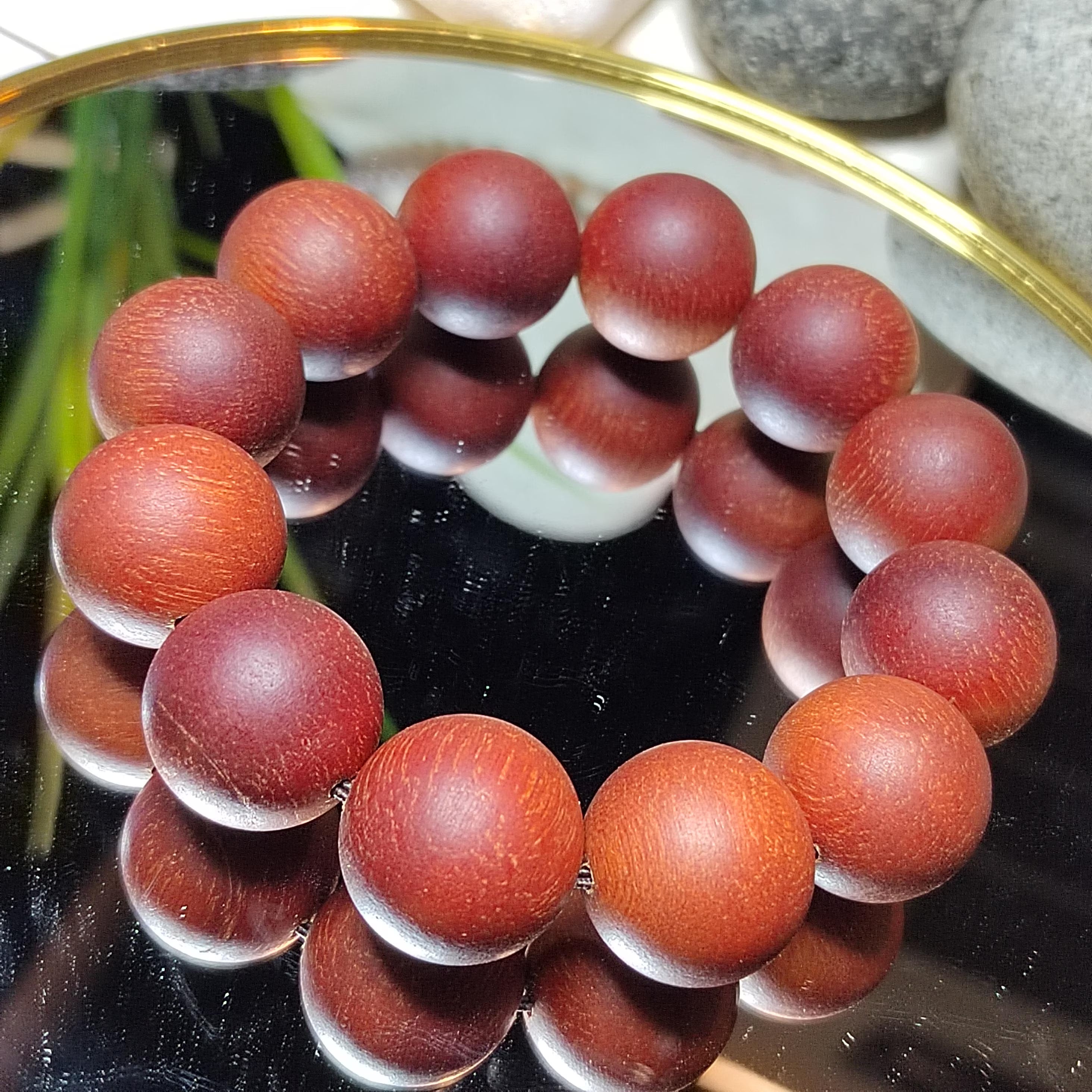 Close-up of a bracelet with red beads on a reflective surface