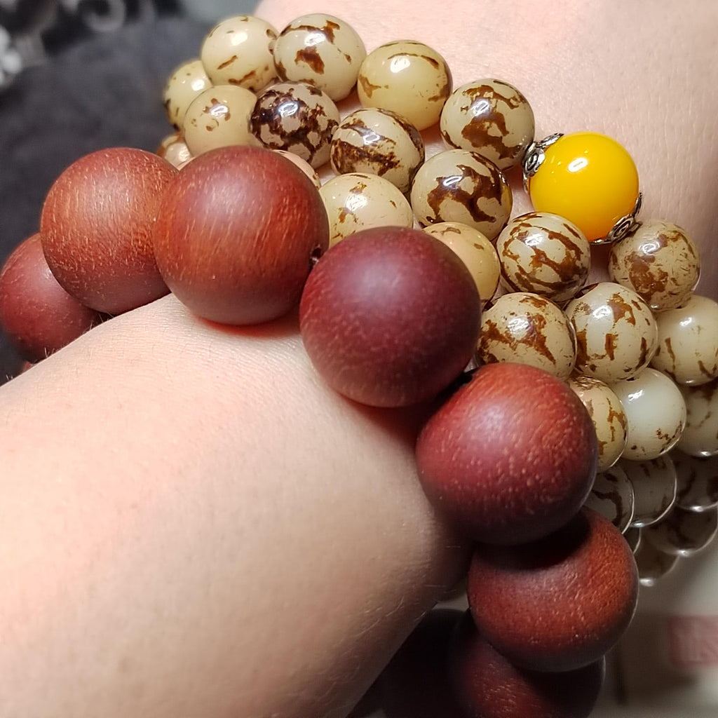 Close-up of a hand wearing a bracelet with red and white beads.
