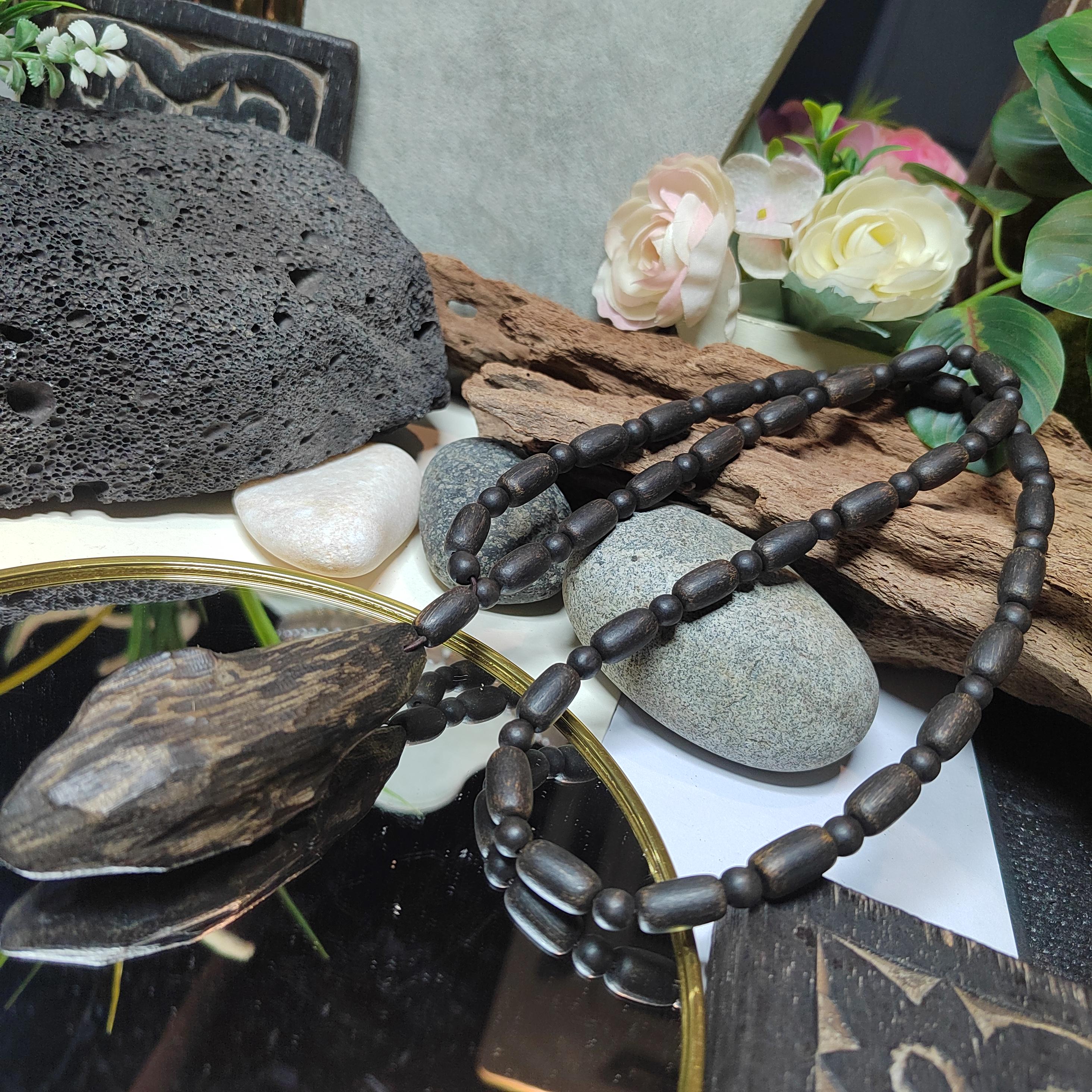 Wooden beaded necklace on a decorative background with stones and flowers