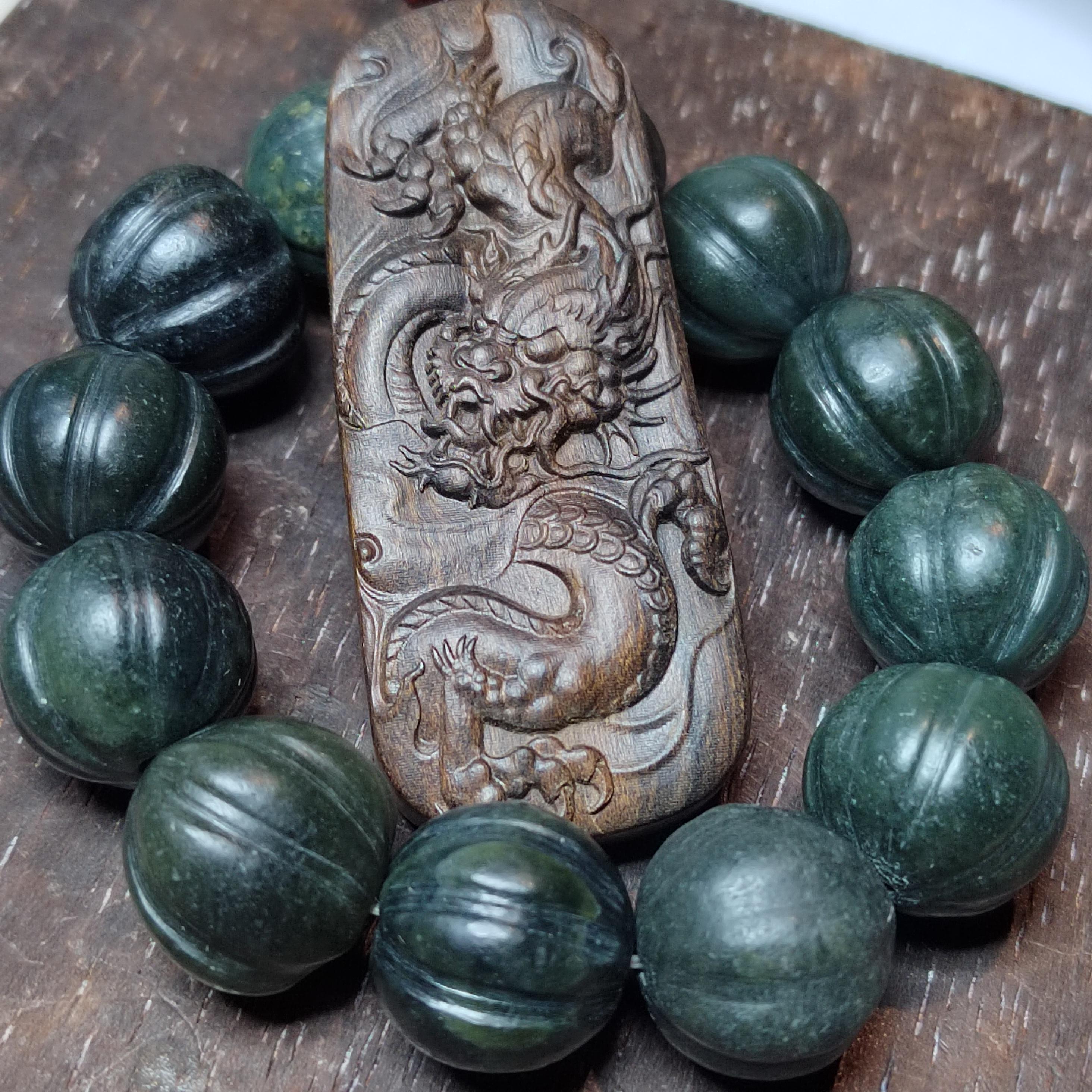 Wooden pendant with dragon design surrounded by green marbled stones on a wooden surface