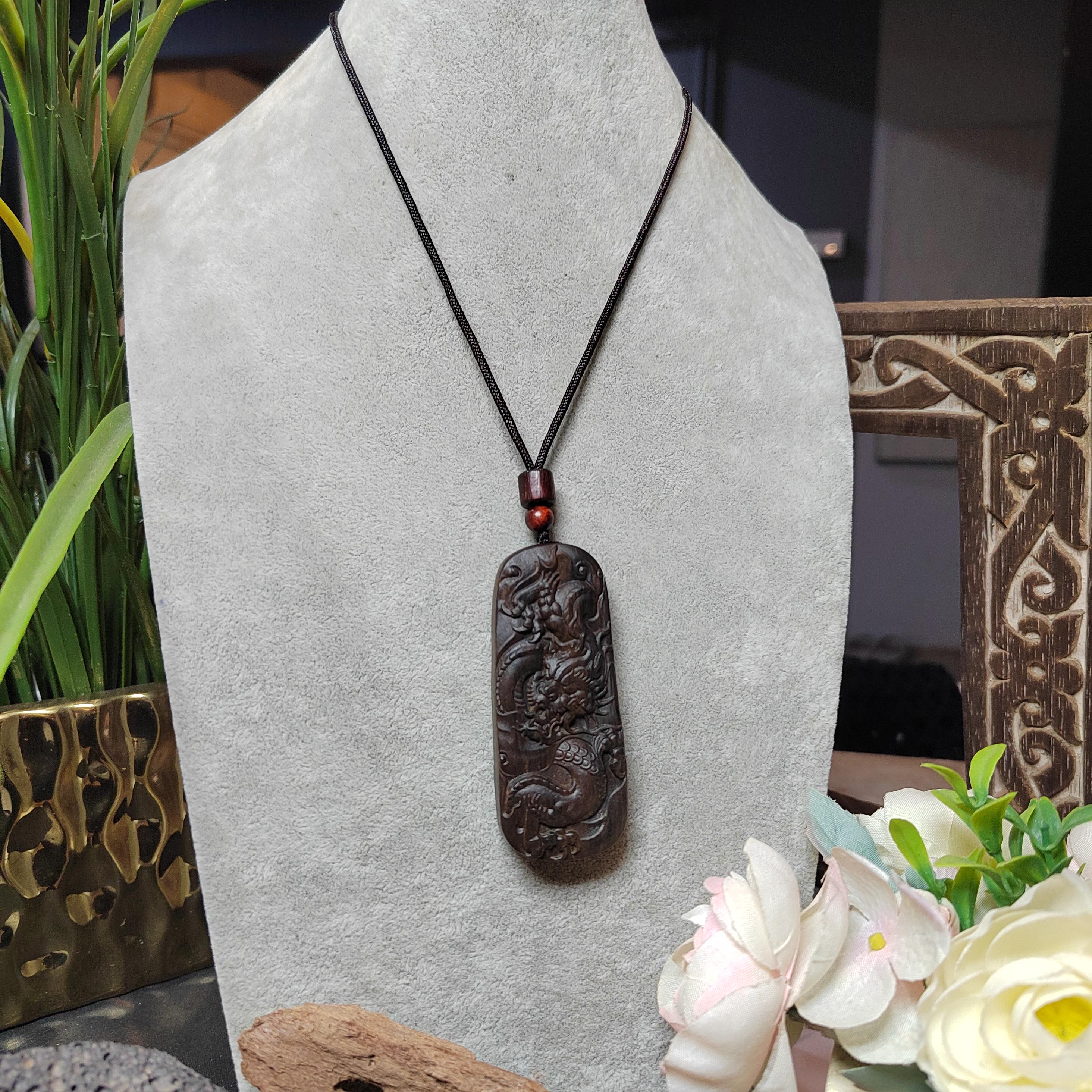 Decorative pendant necklace on a gray stand with flowers and plants in the background