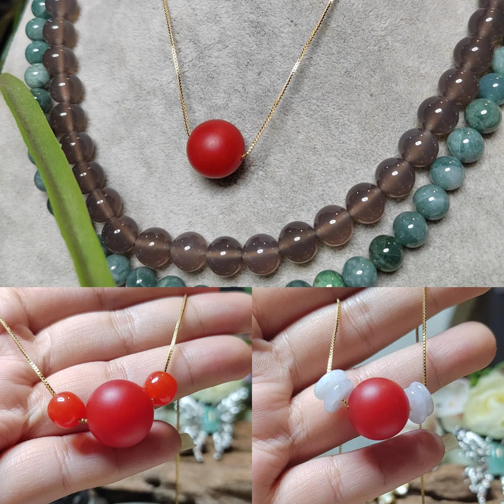 Necklace with red Nanhong beads held by a hand, displayed on a textured surface.