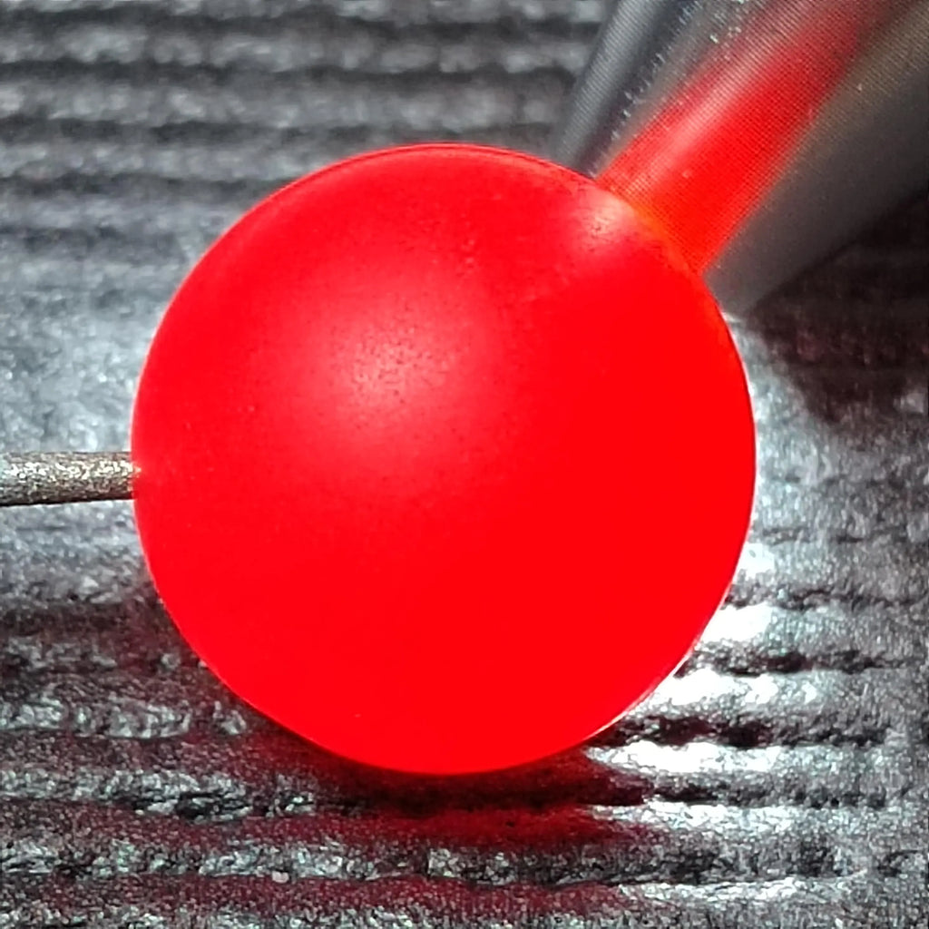 Close-up of a red Nanhong bead on a textured surface