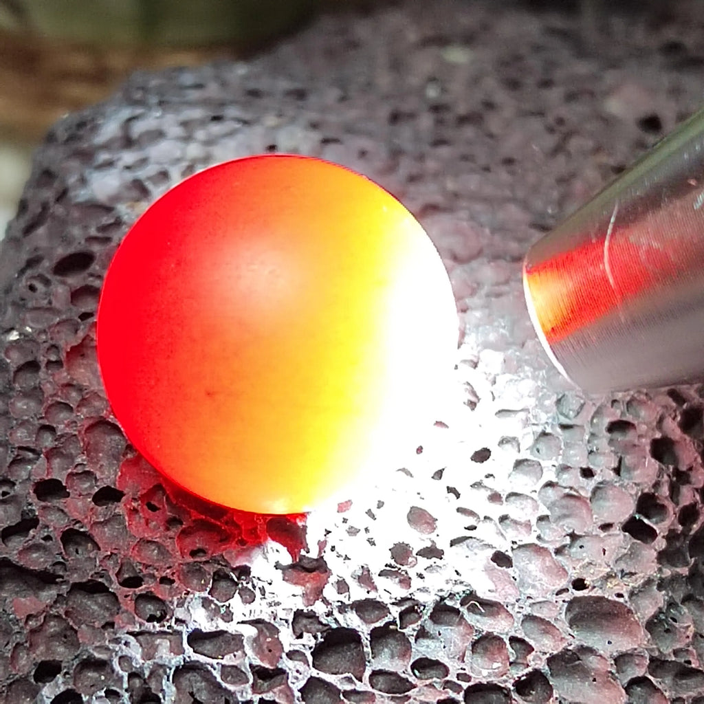 Red Nanhong bead on a textured surface with a tool nearby