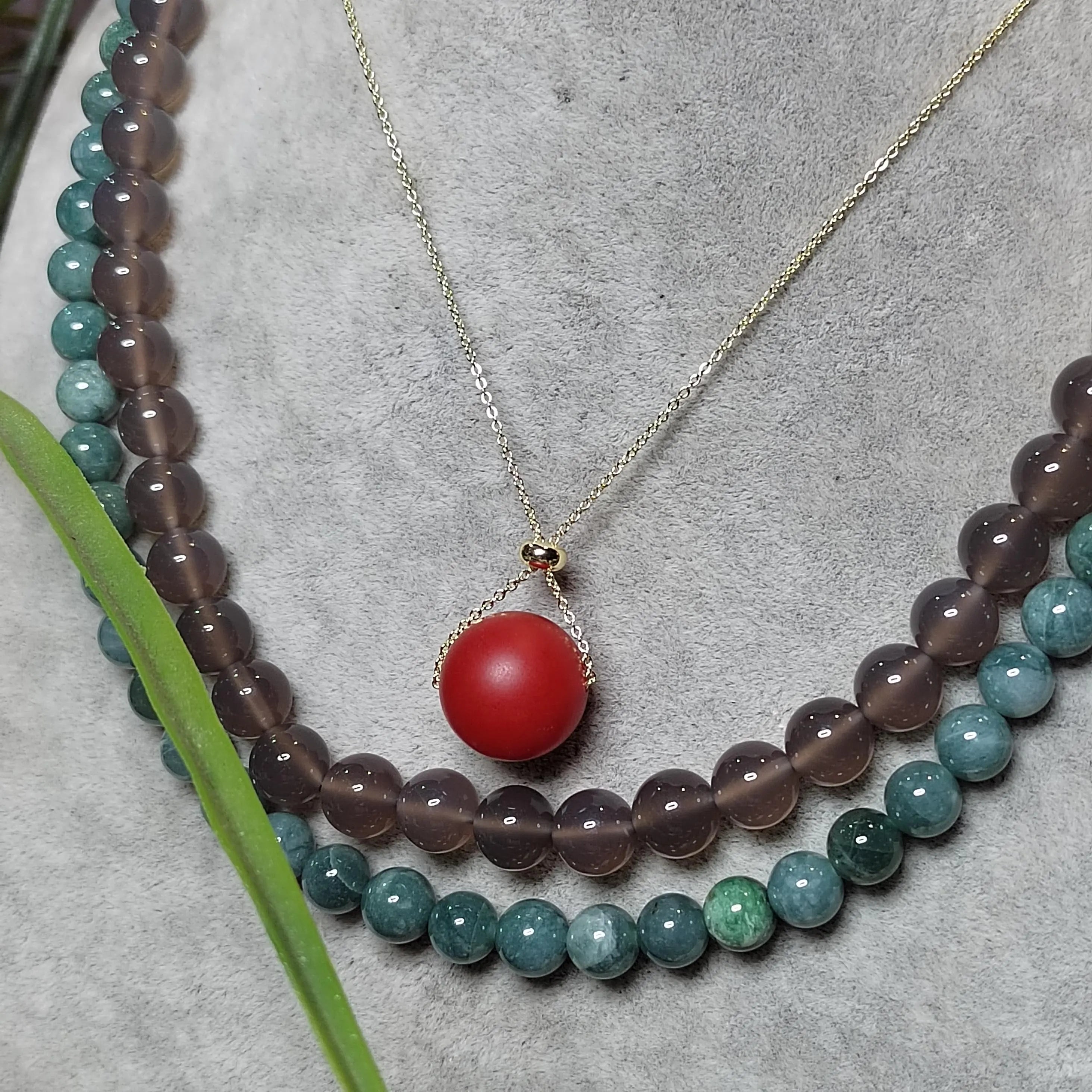 Necklace with multicolored beads and a red Nanhong bead on a textured surface.