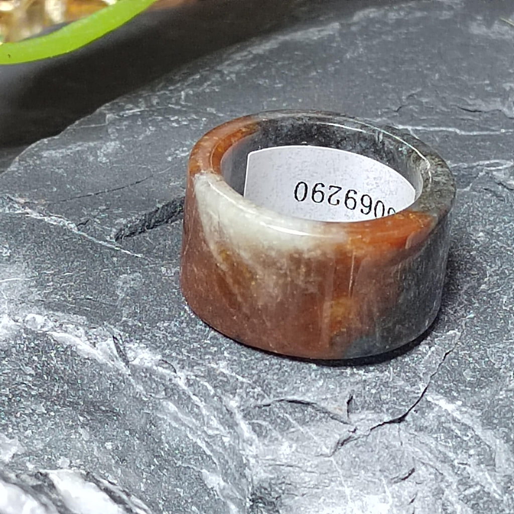 Brown and gray ring on a textured surface with a visible number tag.