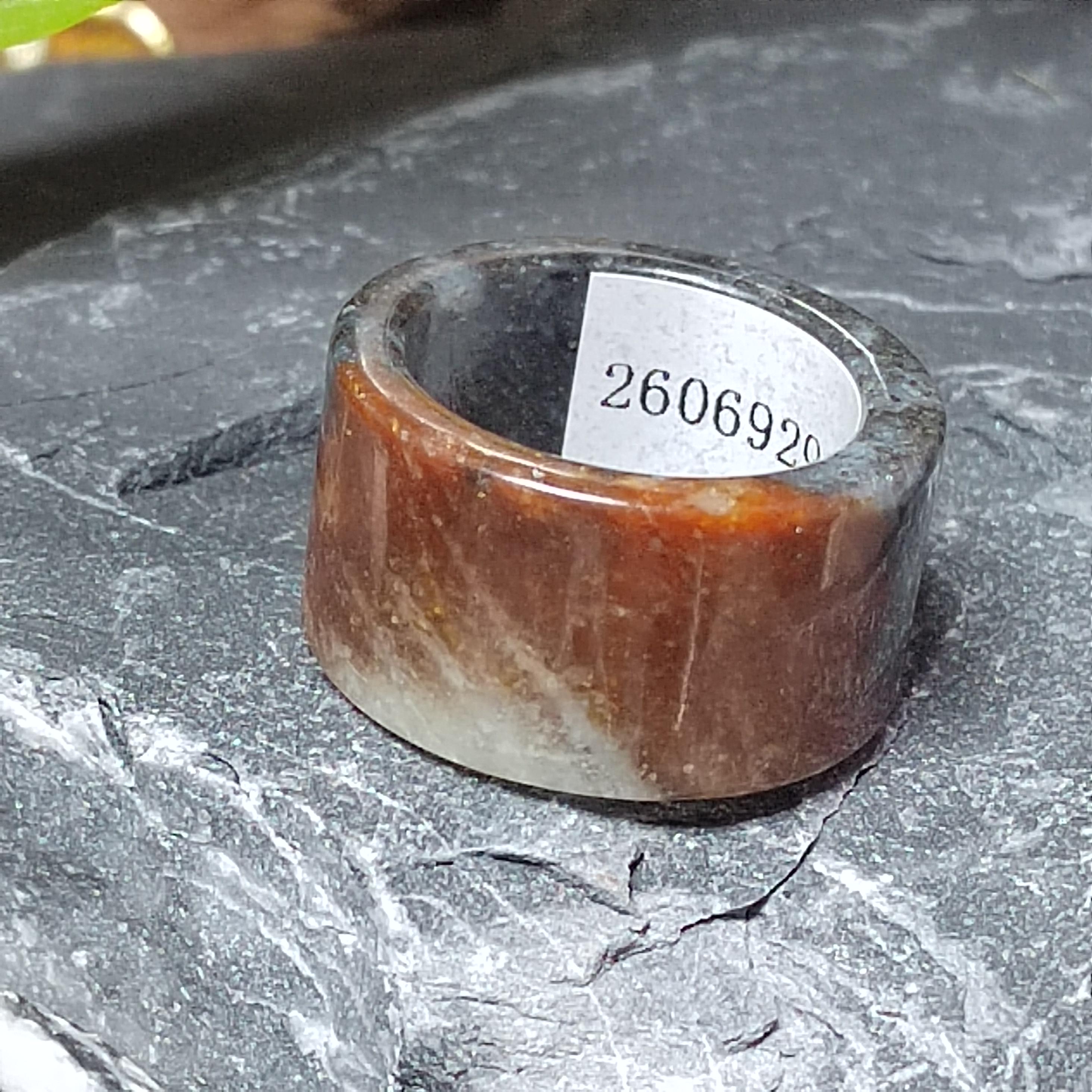 Brown and gray stone ring with a label on a dark surface