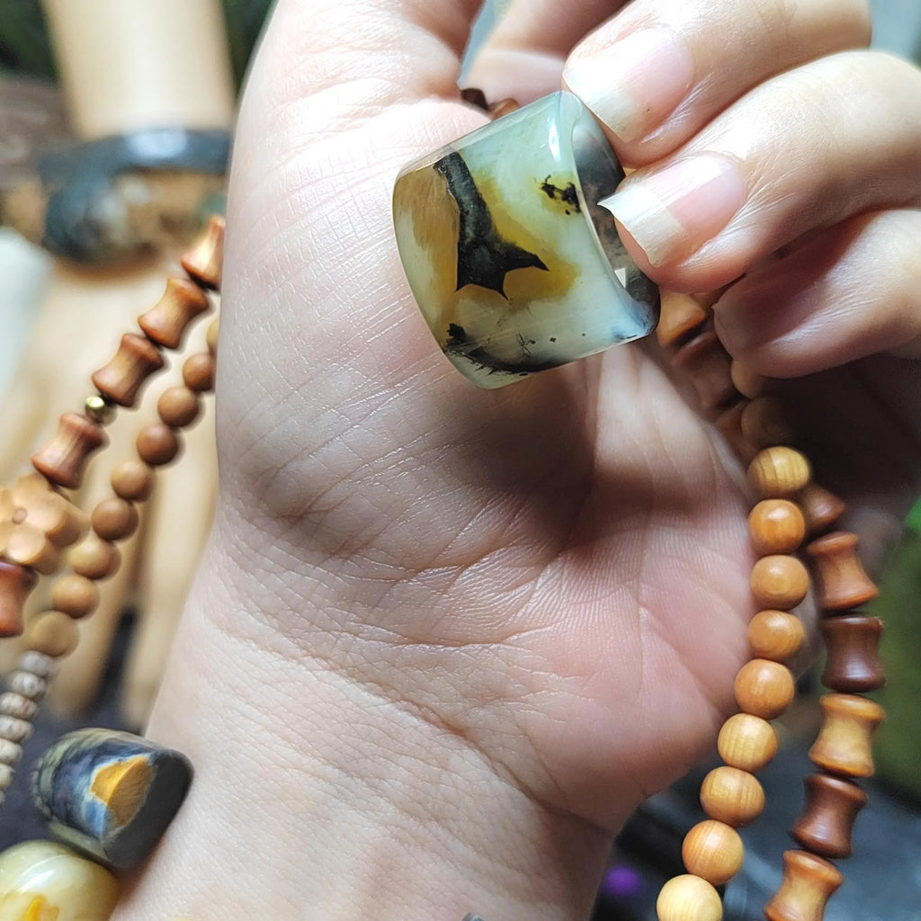Hand holding a piece of amber with a blurred background of wooden beads