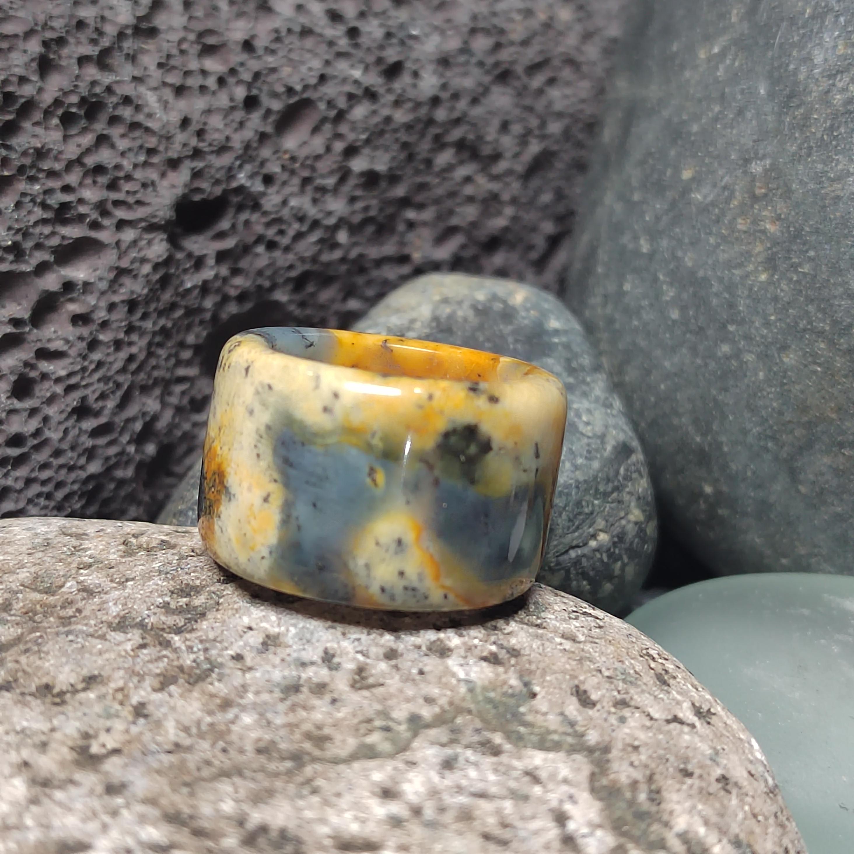 Polished stone ring with multicolored pattern on a textured stone surface