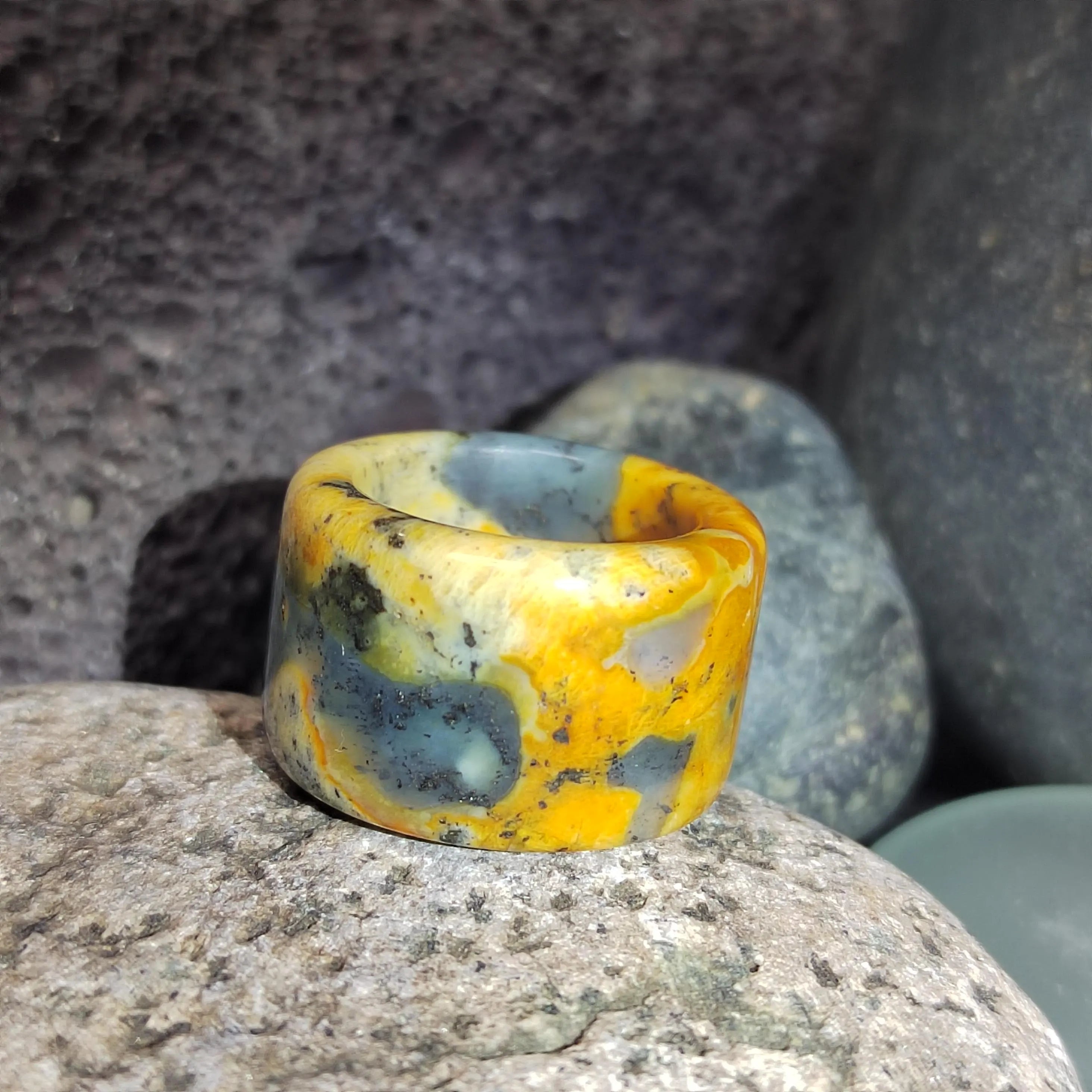 Marbled yellow and blue ring on a stone surface with a natural stone background