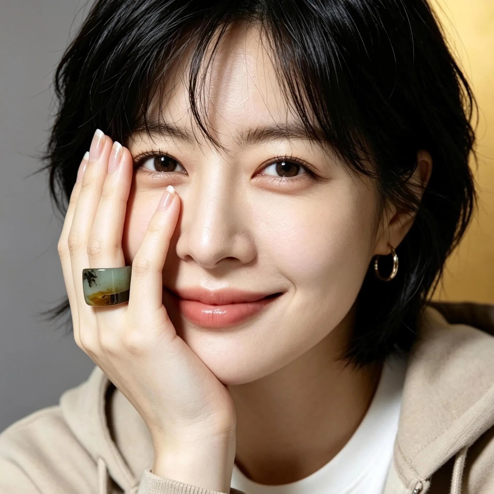 Woman wearing a ring with a scenic design, posing with one hand on her face.