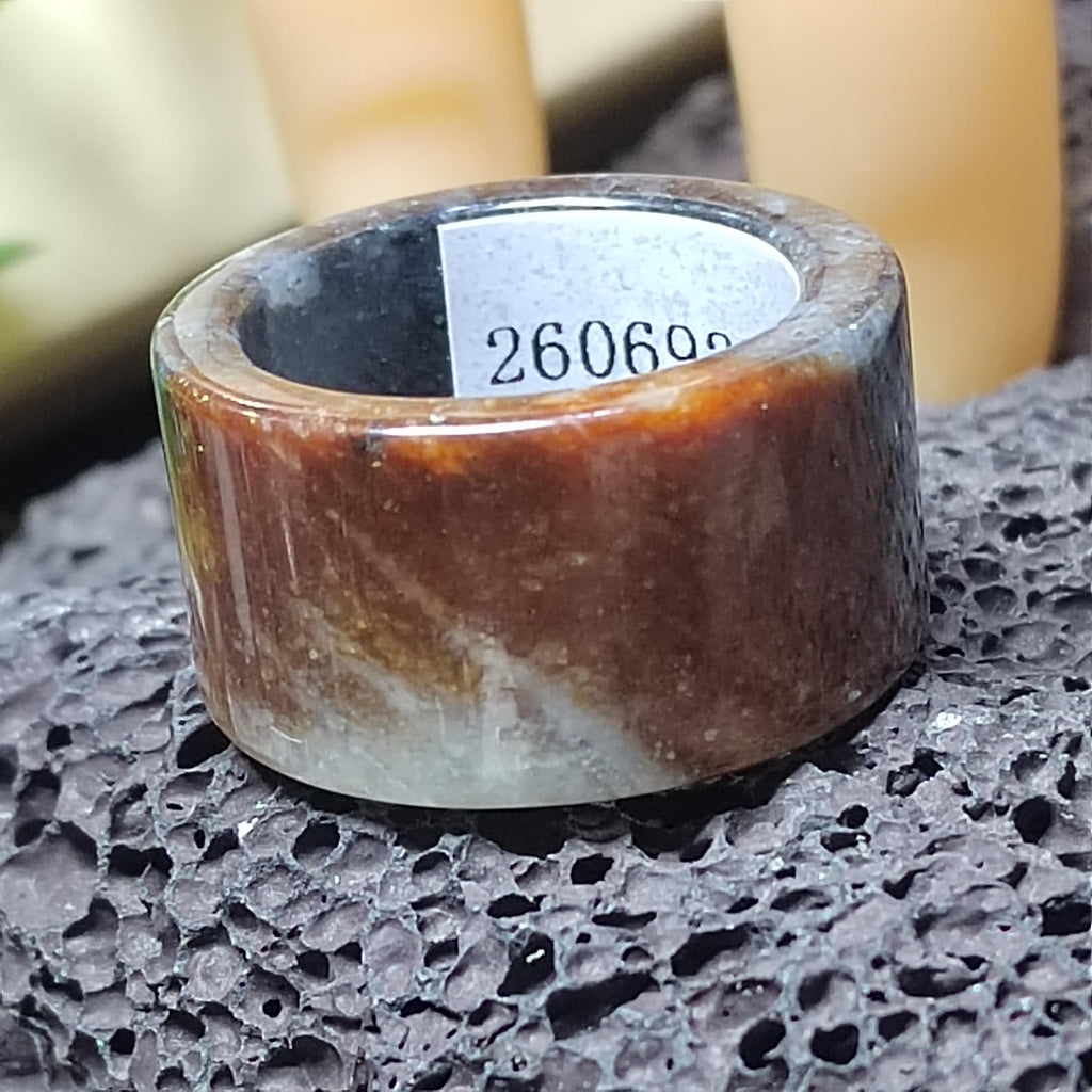 Brown stone ring with a visible brand number on a textured surface