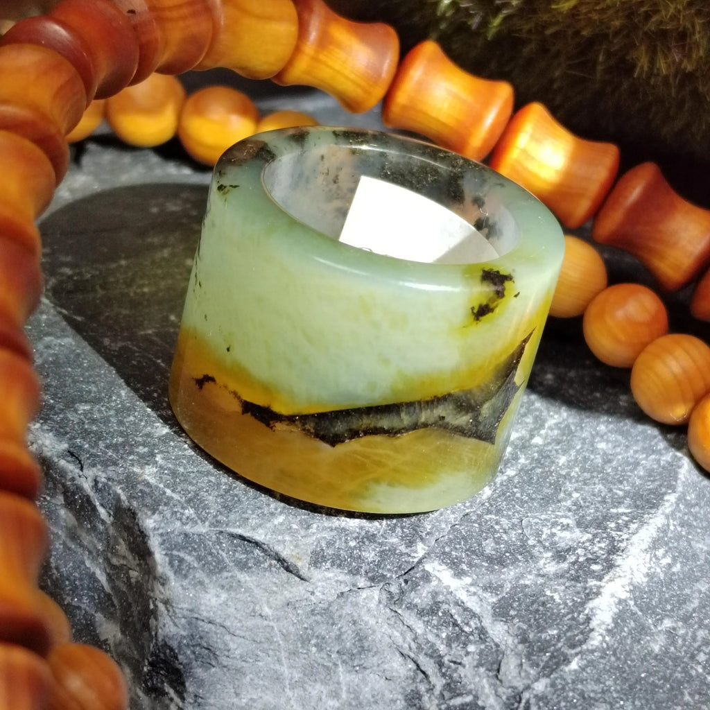 Decorative stone ring with a natural pattern, surrounded by orange beads on a textured surface.