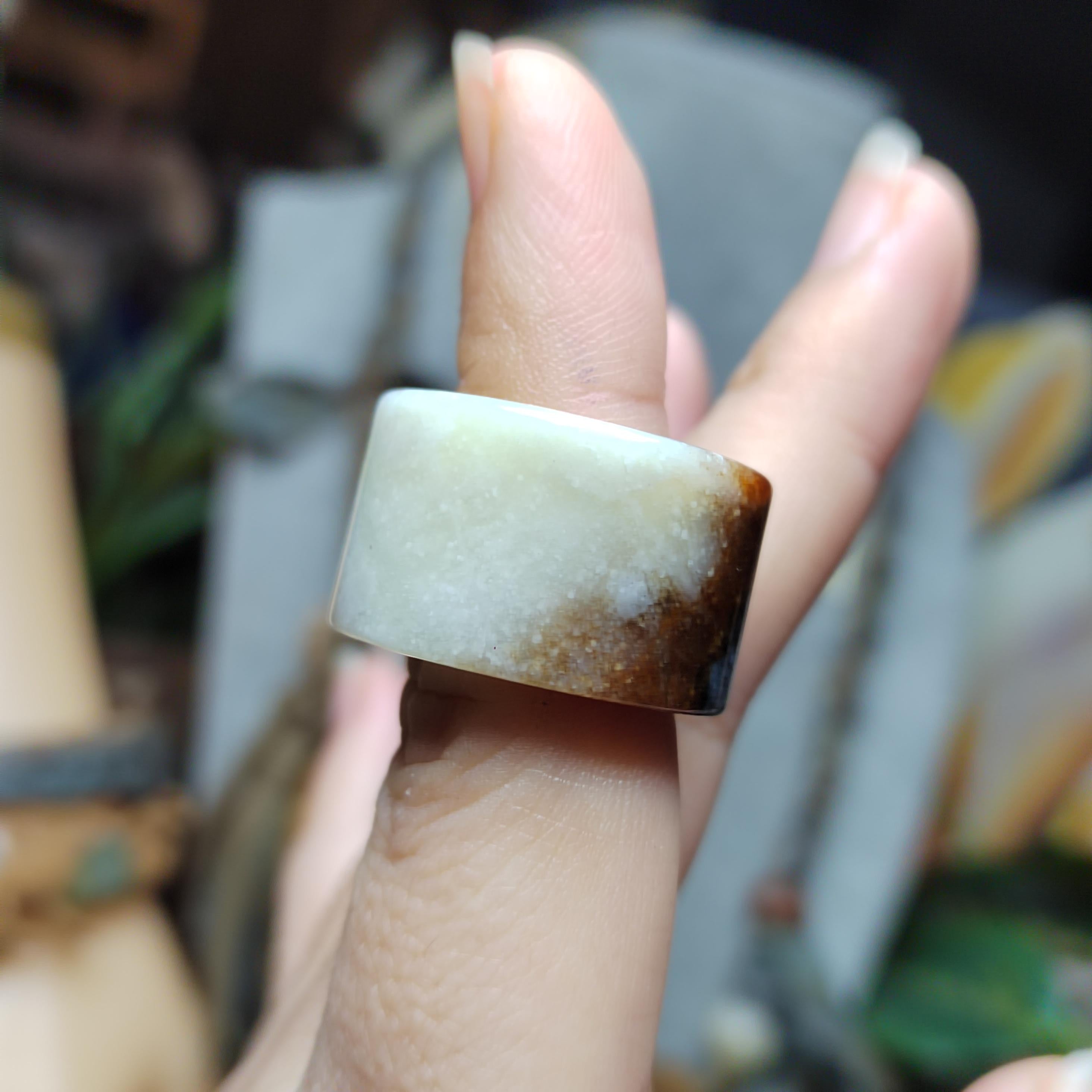 Close-up of a hand wearing a jade ring with a blurred background