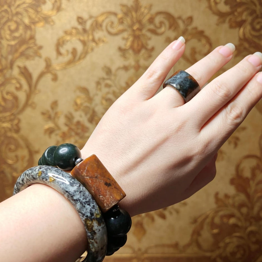 Hand wearing a bracelet and ring with a decorative background