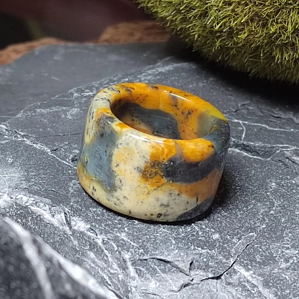 Decorative stone ring with orange and gray patterns on a textured surface