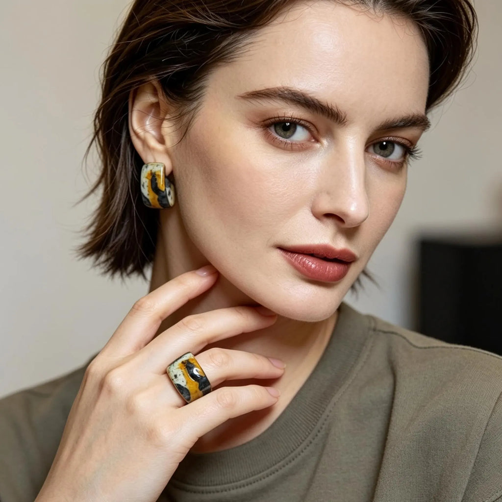 Woman wearing earrings and a ring with a neutral background
