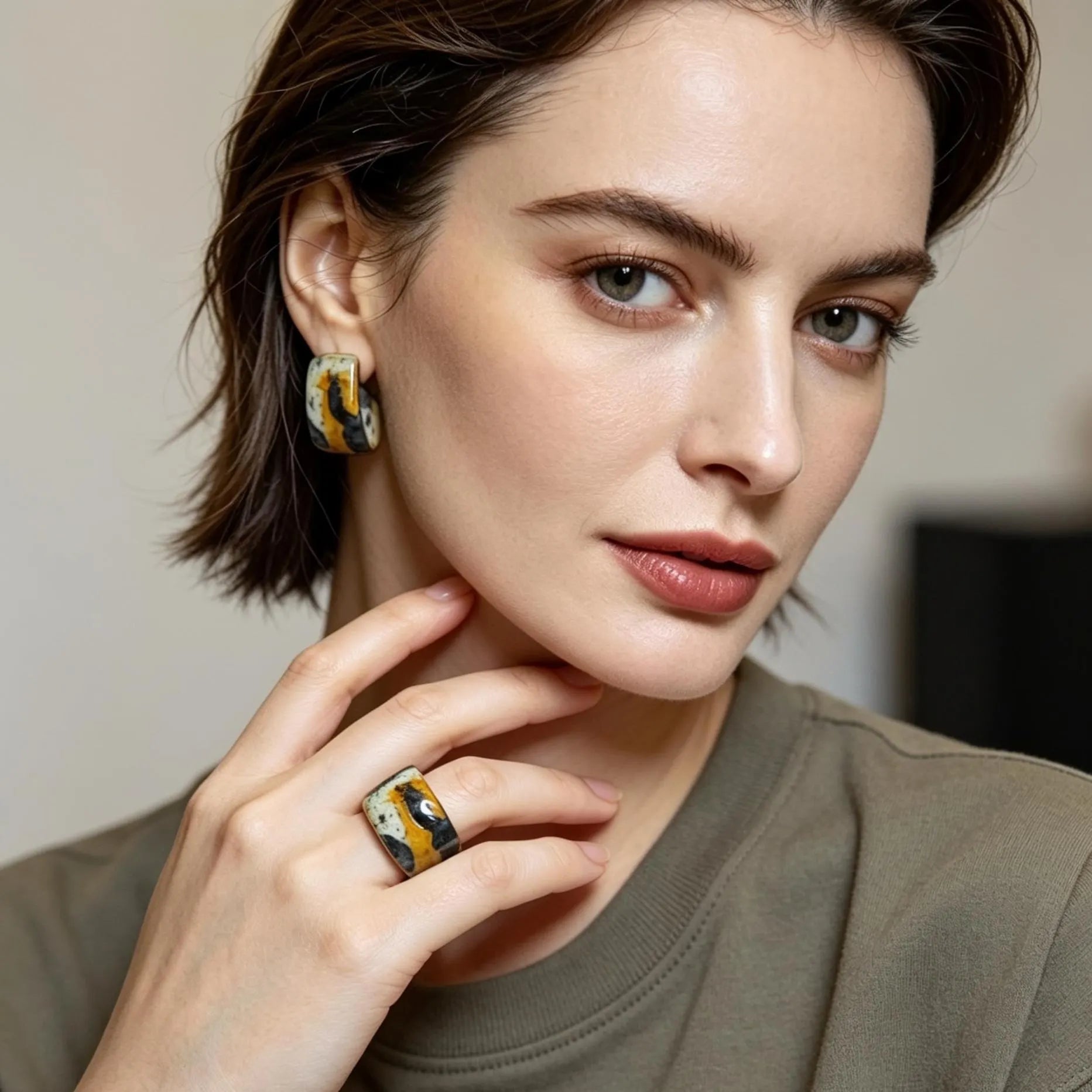 Woman wearing earrings and a ring with a neutral background