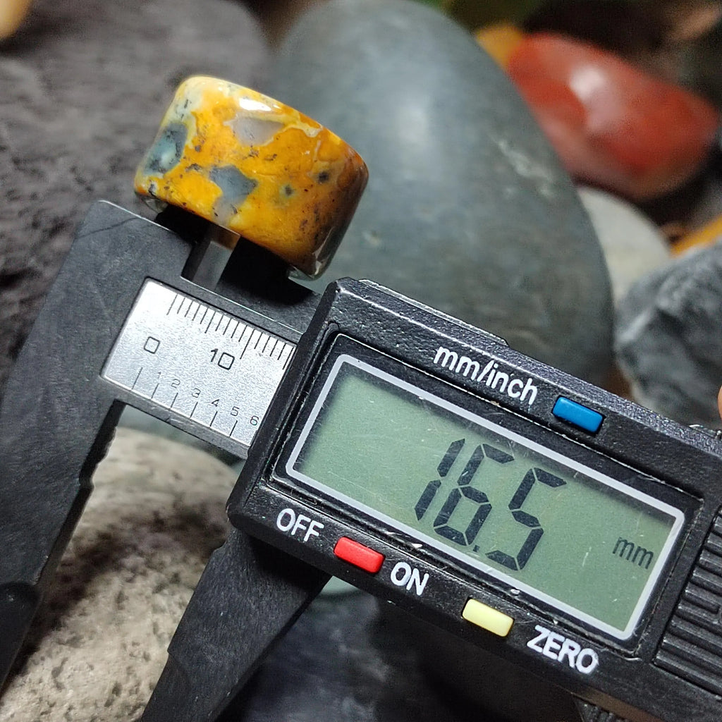 Digital caliper measuring a yellow and brown stone against a rocky background